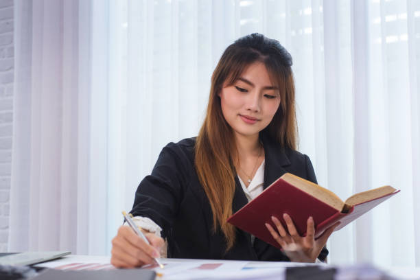 istock Business young women reading book at workplace in office. Knowledge and education concept 1068623036