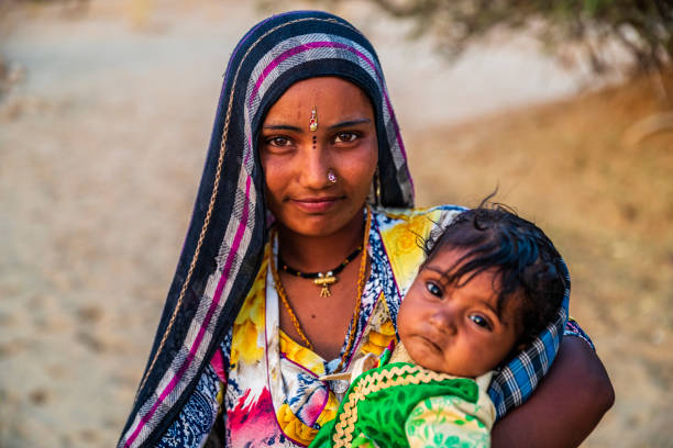 Young Indian woman holding her baby, desert village, India Young Indian woman with her baby. Thar Desert, Rajasthan, India. india poverty stock pictures, royalty-free photos & images