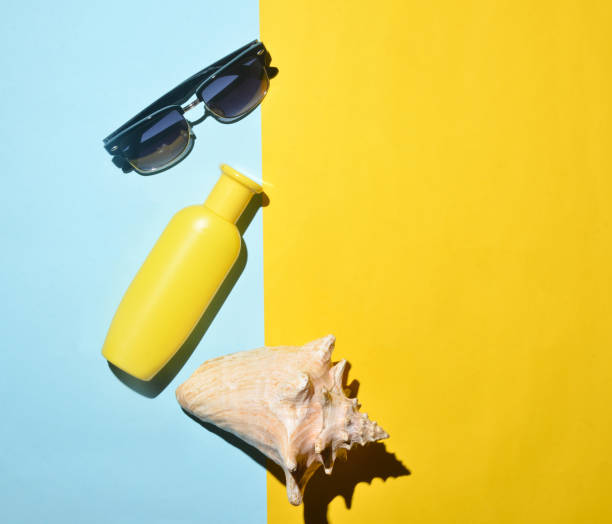 istock Sunglasses, sunblock, shell on a blue yellow background. Summer beach resort. Top view. 1068631278