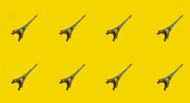 Creative background of statuettes of the eiffel tower on a yellow surface. Top view.