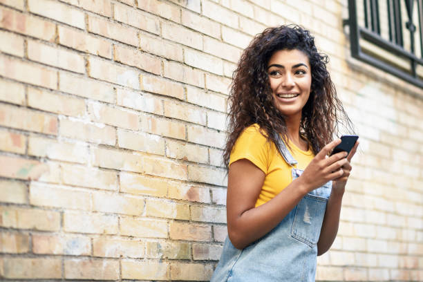 istock Happy Arab girl using smart phone on brick wall. 1068651668
