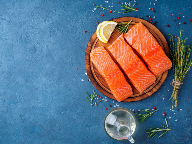 fond de nourriture, tranchés darnes de portions grand filet de saumon sur planche à découper sur le sombre tableau béton bleu, copie espace, vue de dessus - salmon photos et images de collection