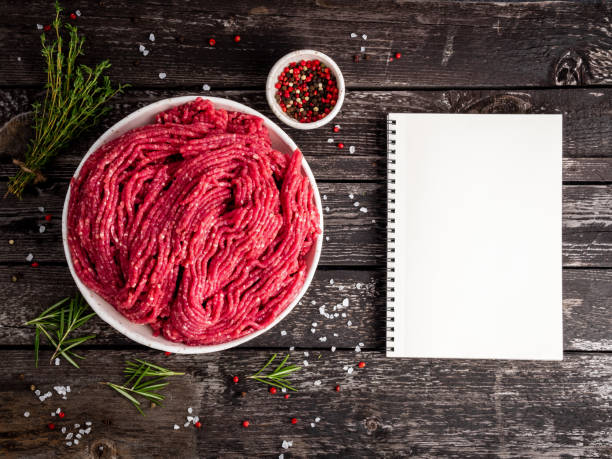 Mince beef, ground meat with ingredients for cooking on old gray dark wooden rustic table, notepad, recipe mock-up, top view, copy space Mince beef, ground meat with ingredients for cooking on old gray dark wooden rustic table, notepad, recipe mock-up, top view, copy space. beef pad stock pictures, royalty-free photos & images