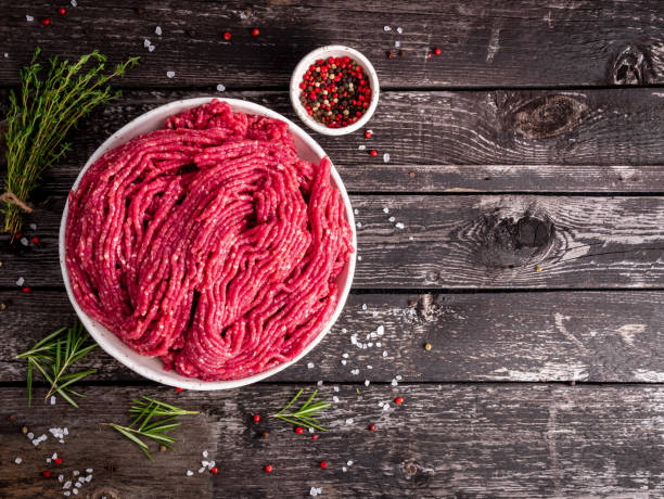 Mince beef, ground meat with ingredients for cooking on old gray dark wooden rustic table, top view, copy space