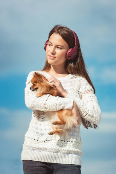 niña de 14 años en un auriculares escuchando una música de un teléfono inteligente en una playa. contra un cielo azul. cierre para arriba - pampered pets audio fotografías e imágenes de stock