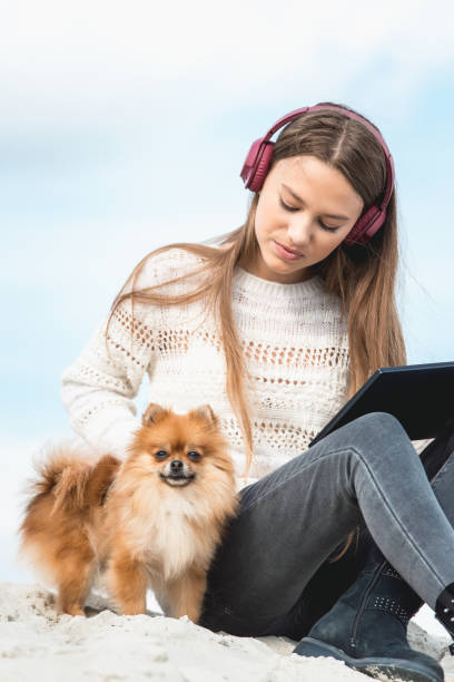 niña de 14 años en un auriculares escuchando una música de un teléfono inteligente en una playa. contra un cielo azul. cierre para arriba - pampered pets audio fotografías e imágenes de stock