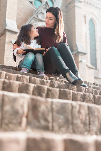 matka i córka czytają historie z książki przed kościołem w niedzielę - book child staircase steps zdjęcia i obrazy z banku zdjęć