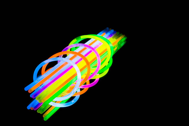 colorido fluorescente luz néon brilham pulseira de pulseira bracelete vara e tubos em fundo preto de reflexão de espelho - led toys - fotografias e filmes do acervo