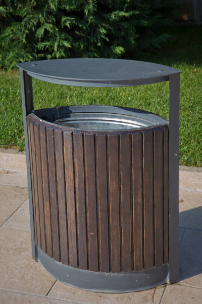 istock black garbage bin inside a wooden enclosure at a park. copy space on the left. Rubbish box in the park . 1068703406