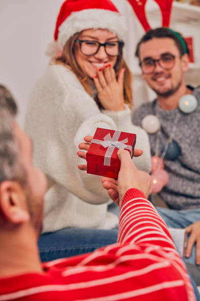 zazdrosny mężczyzna patrząc na swoją dziewczynę otrzymującą prezent świąteczny od kochanka. - women celebration wine party zdjęcia i obrazy z banku zdjęć