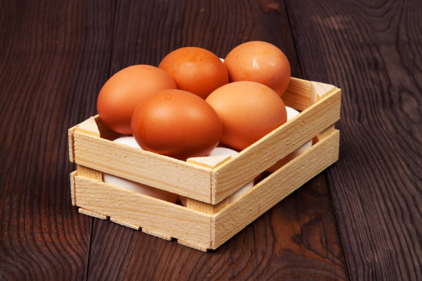 White and brown eggs in wooden crate on wooden background.