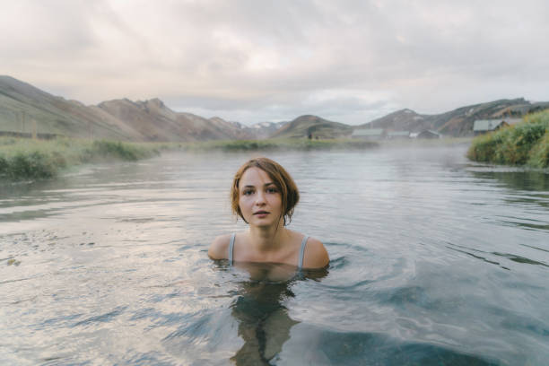 Woman resting in hot natural pool in Iceland Young Caucasian woman resting in hot natural pool in Iceland woman cold water swimming stock pictures, royalty-free photos & images