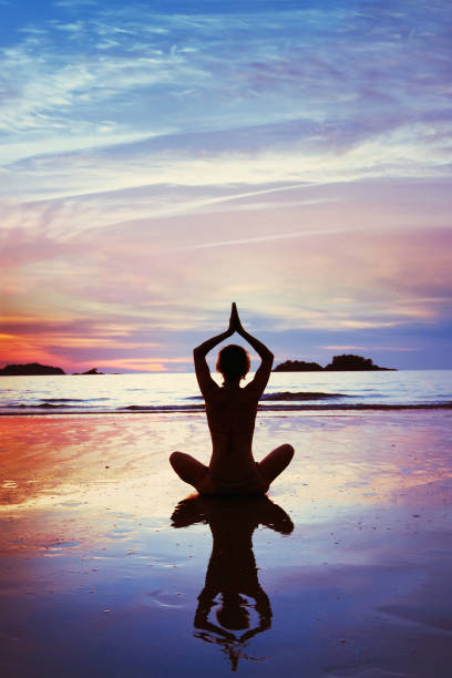 yoga, silhouette of woman meditating on the beach. - beautiful blue sport vertical imagens e fotografias de stock