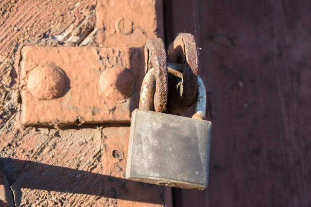 Rusty chain and old padlock hang on a timber farm fence post in rural New South Wales, Australia