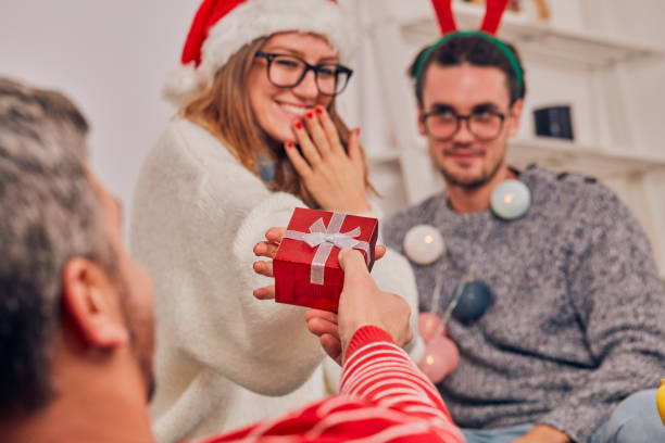 zazdrosny mężczyzna patrząc na swoją dziewczynę otrzymującą prezent świąteczny od kochanka. - women celebration wine party zdjęcia i obrazy z banku zdjęć