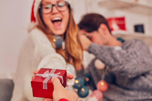 zazdrosny mężczyzna patrząc na swoją dziewczynę otrzymującą prezent świąteczny od kochanka. - women celebration wine party zdjęcia i obrazy z banku zdjęć