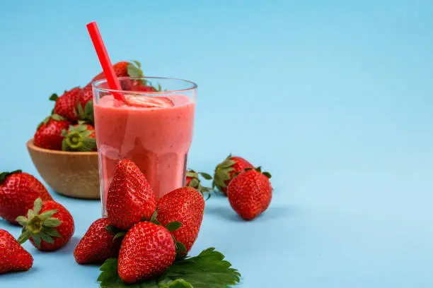 fresh strawberrysmoothie or milkshake on a delicately blue background.