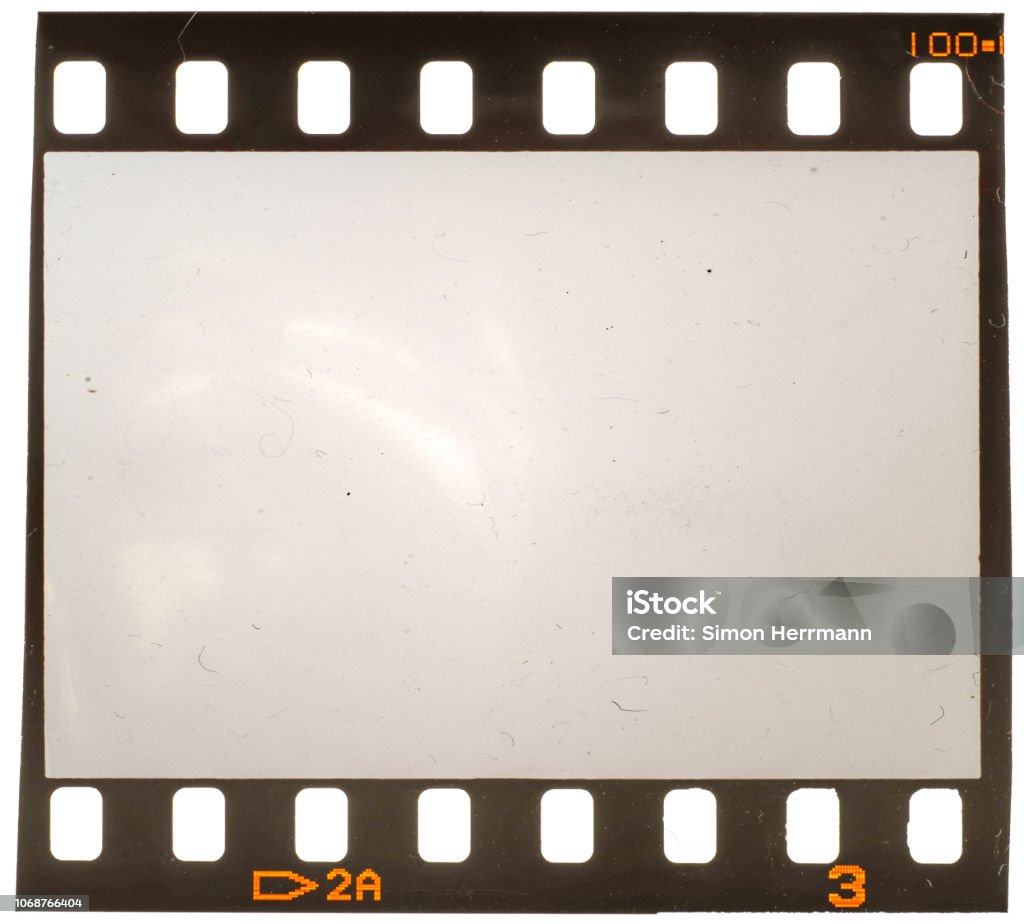 Real macro photo of old and grungy 35mm film frame or strip on white with signs of usage, dust and film grain Perfect placeholder for your image to let it look retro or vintage Movie Stock Photo
