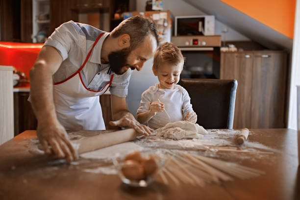 istock Cute little baker and his father making a bread 1068773592
