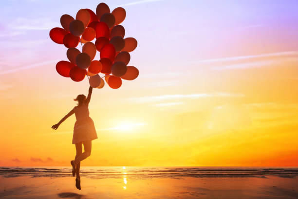 glück oder traum konzept, silhouette der glückliche frau springen mit bunten luftballons - beach ideas stock-fotos und bilder