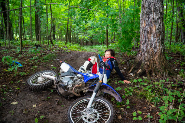 The motorcyclist is riding in the forest in the evening