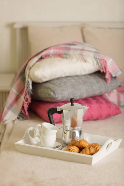 istock Breakfast in bed. On a white wicker tray there is a coffee maker, coffee cups and croissants. 1068776150