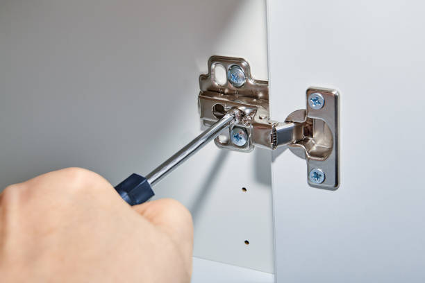 istock Handyman adjusts hinges on door of office table. 1068777996