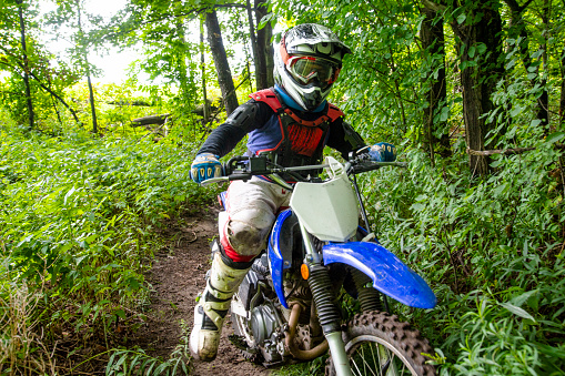 A young dirt bike rider in the woods.