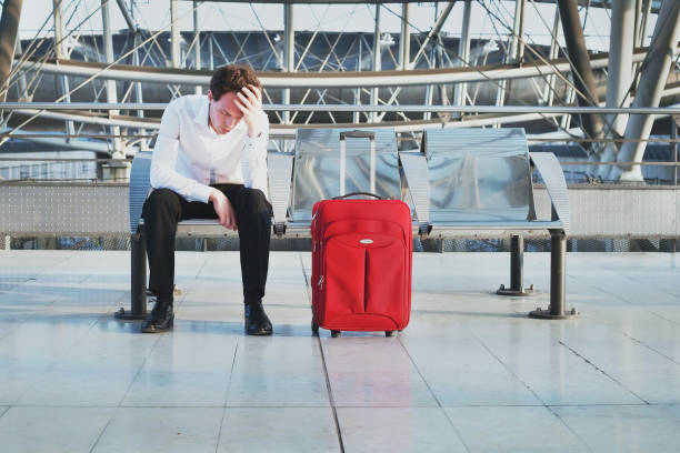 flight delay or problem in the airport, tired desperate passenger waiting in the terminal flight delay or problem in the airport, tired desperate passenger waiting in the terminal with suitcase delayed sign photos stock pictures, royalty-free photos & images