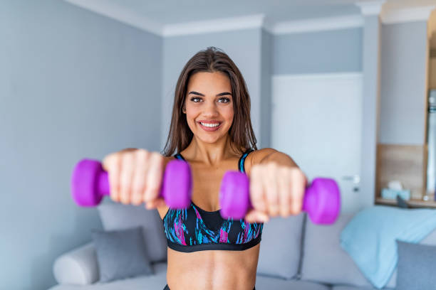 istock Beautiful smiling woman practising with dumbbells at home 1068783134