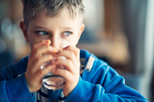 Portrait of a cute little boy drinking a glass of water