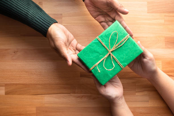Male gives a gift present to female with wooden copy space background.happiness moment Male gives a gift present to female with wooden copy space background.happiness moment concepts ideas anniversary gifts stock pictures, royalty-free photos & images