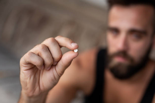 Man taking ecstasy pill Man holding an ecstasy pill. Focus on the pill self destructive stock pictures, royalty-free photos & images