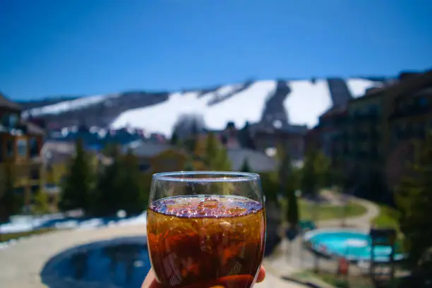 A Cold drink in a nice glass with ski slopes in the background.