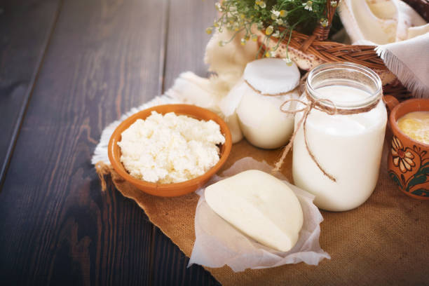 Una lata de leche y otros productos lácteos en la mesa. Naturaleza muerta en estilo rural. Productos lácteos de la vaca del agricultor - foto de stock