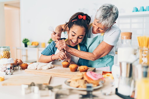 Grandmother and granddaughter preparing cupcakes together