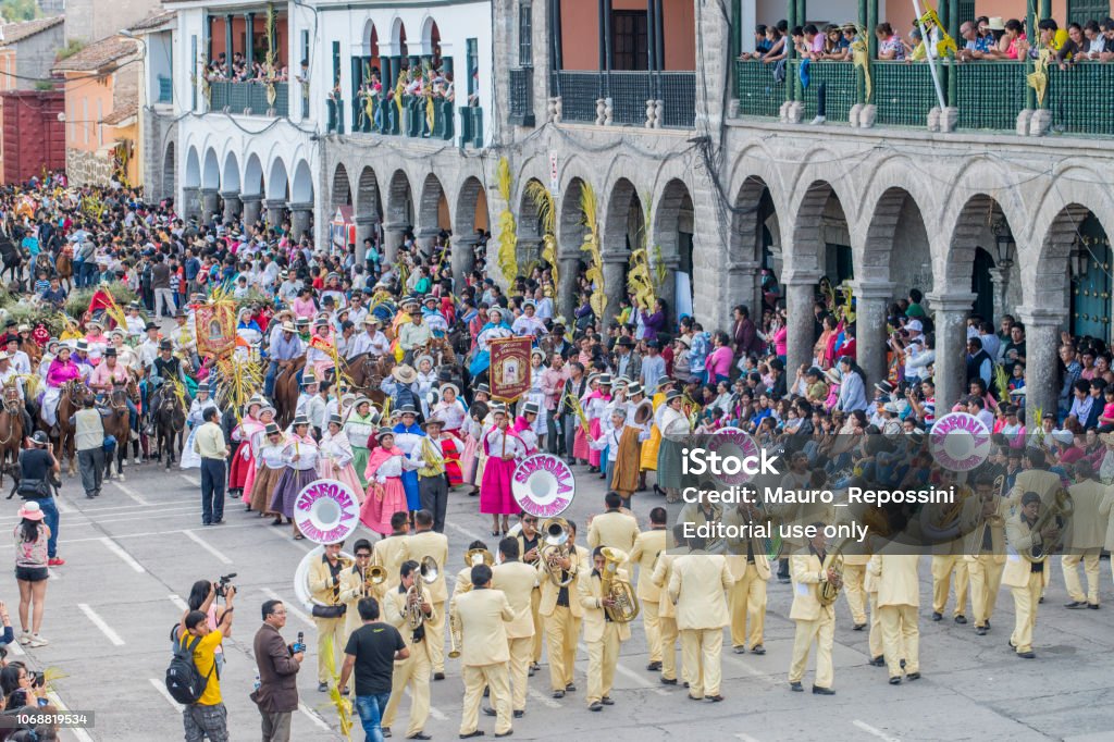 People with multicolored dresses and hats and a marching band during the celebration of the Palm Sunday of Easter at Ayacucho city, Peru. People with multicolored dresses and hats and a marching band during the celebration of the Palm Sunday of Easter in the streets of the main square of Ayacucho, the capital city of the Huamanga Province, Peru.
Ayacucho is the "City of Churches" and it is very famous for the impressive Holy Week celebration every year. Andean Highlands Stock Photo