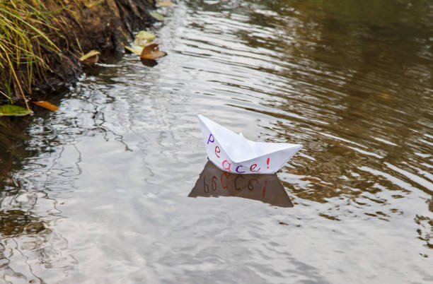 istock lonely white paper boat called peace floating on a stream 1068825280