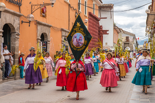 People with multicolored dresses and hats marching during the celebration of the Palm Sunday of Easter in the streets of the main square of Ayacucho, the capital city of the Huamanga Province, Peru.\nAyacucho is the \
