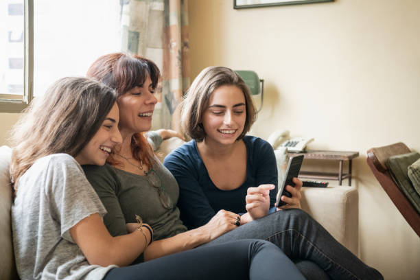 istock Mother and daughters on sofa with smartphone 1068831146