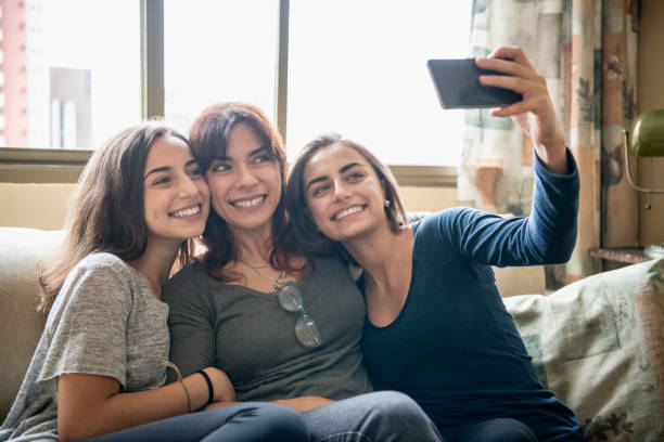 madre e hijas teniendo selfie en teléfono - women sofa teenage girls hairstyle fotografías e imágenes de stock