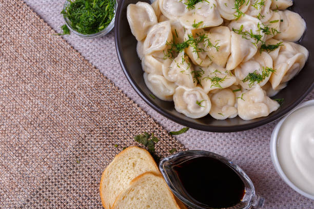 boiled dumplings national dish of many nations with sour cream, soy sauce and greens - fotografia de stock