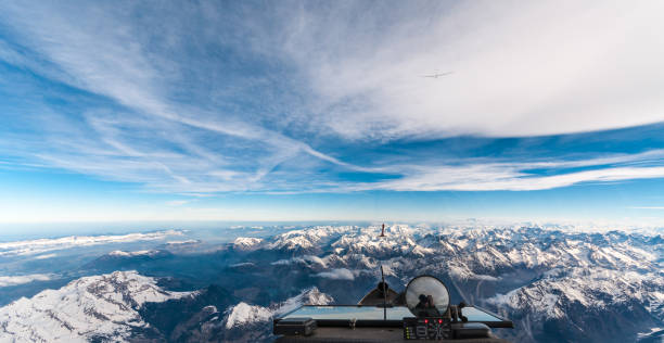View from the cockpit of a glider Looking forward from the cockpit of a glider in flight over snow-capped mountains and interesting clouds in the sky oxygen mask plane stock pictures, royalty-free photos & images