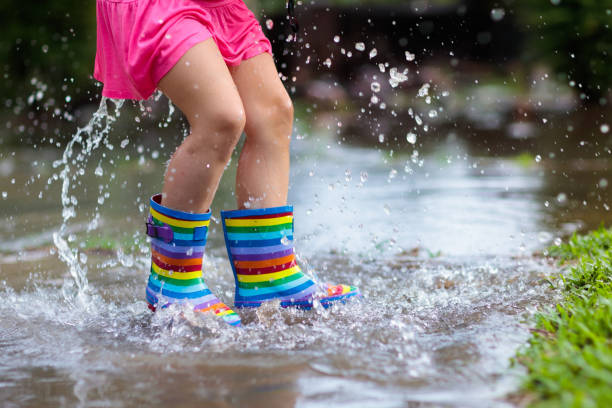 istock Kid with umbrella playing in summer rain. 1068861304