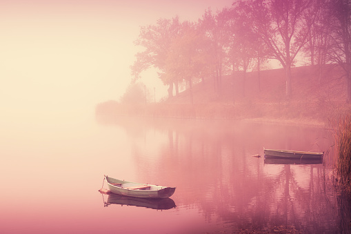 Boats floating on a calm misty lake. Stylized for a retro photo. Masuria, Poland.