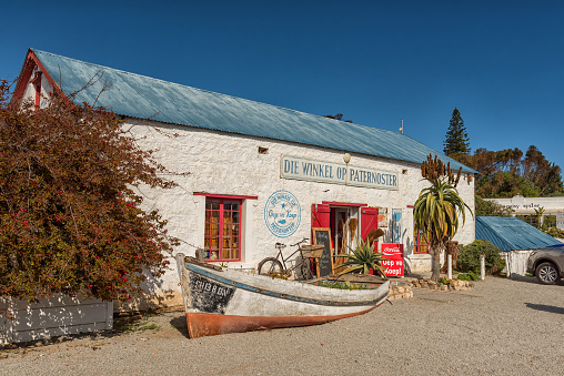 PATERNOSTER, SOUTH AFRICA, AUGUST 21, 2018: Die Winkel Op Paternoster, a shop in an historic building in Paternoster on the Atlantic Ocean Coast. A boat and bicycle are visible