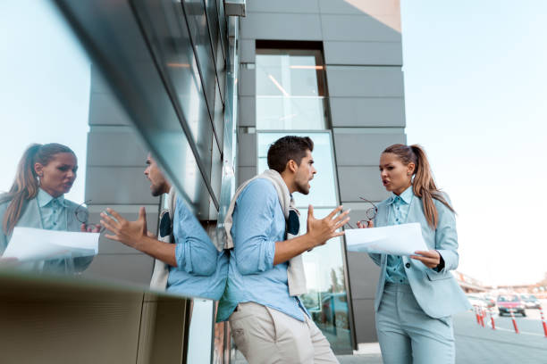 istock Coworkers arguing about new project while standing outdoors. Woman holding paperwork. 1068872208