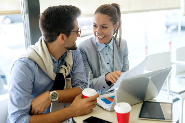 istock Coworkers working on project while sitting in cafe. On desk laptop, tablet and disposable cups with coffee. 1068872466
