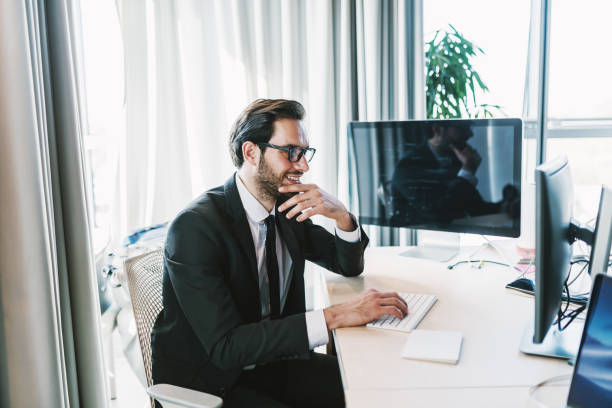 istock Businessman using desktop computer while sitting in his office. One hand on chin and other on keyboard. 1068878718