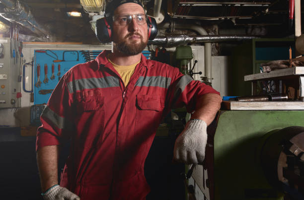 istock Worker in red uniform operating in manual lathe in metal big workshop. 1068879744